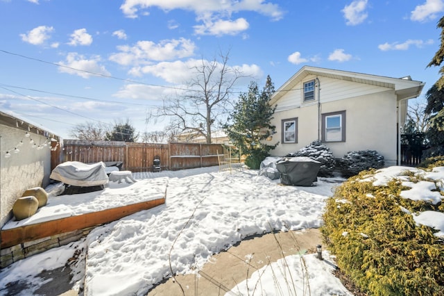 snowy yard with a fenced backyard