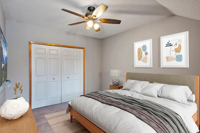 bedroom with vaulted ceiling, a textured ceiling, carpet floors, a closet, and ceiling fan