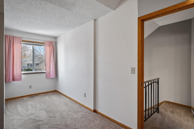 spare room with a textured ceiling and carpet