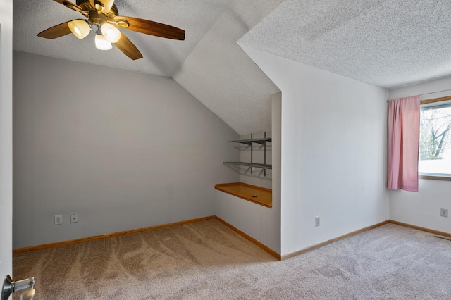 additional living space with ceiling fan, vaulted ceiling, light carpet, and a textured ceiling