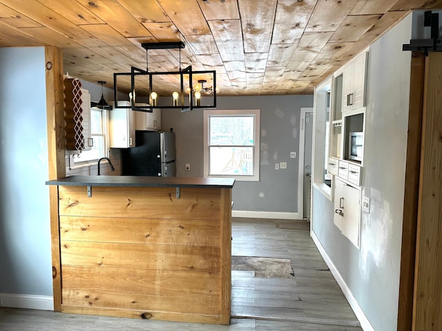 kitchen featuring a kitchen breakfast bar, stainless steel fridge, kitchen peninsula, and wooden ceiling