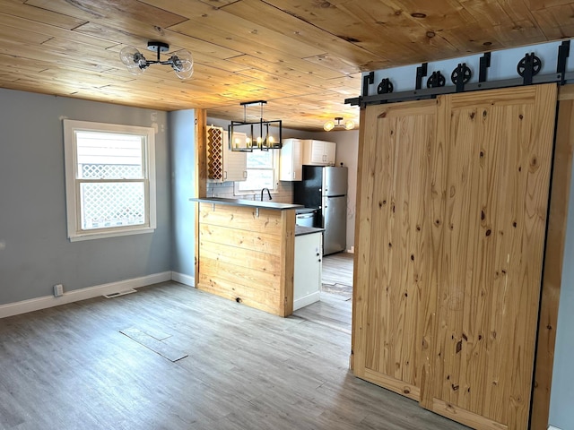 kitchen with hanging light fixtures, wooden ceiling, stainless steel fridge, kitchen peninsula, and light hardwood / wood-style floors