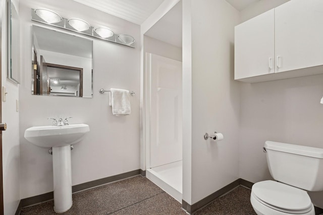 bathroom with toilet, a shower, baseboards, and a sink