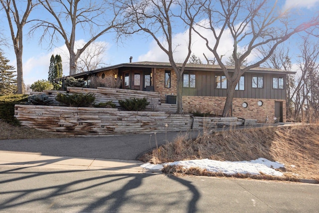 mid-century inspired home featuring brick siding and board and batten siding