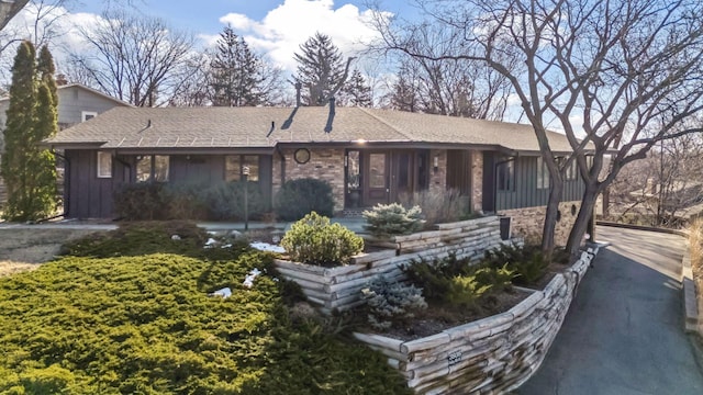 ranch-style house with board and batten siding and a shingled roof