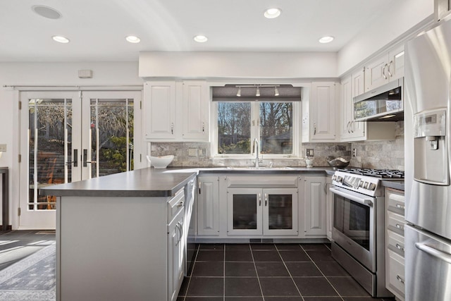 kitchen featuring a peninsula, a sink, stainless steel appliances, dark countertops, and dark tile patterned floors