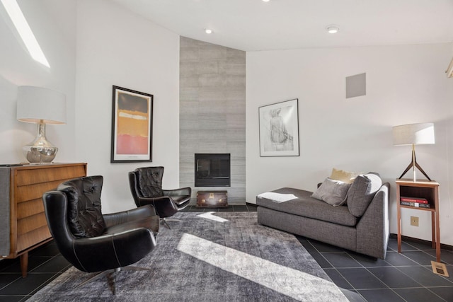 living area with dark tile patterned floors, a tiled fireplace, and high vaulted ceiling