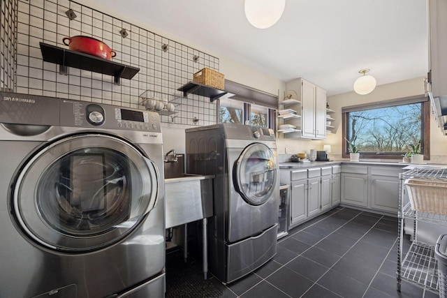 laundry room featuring cabinet space, separate washer and dryer, and dark tile patterned floors