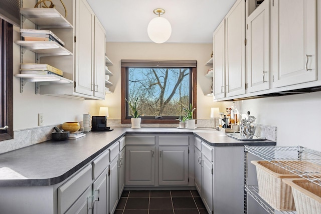 kitchen featuring open shelves, dark countertops, dark tile patterned floors, and gray cabinets