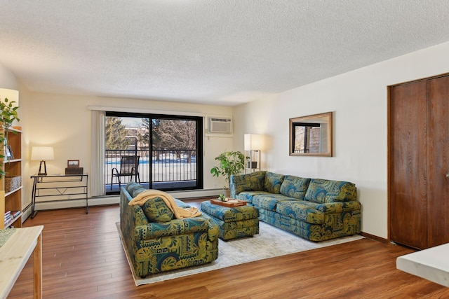 living room featuring a baseboard heating unit, wood-type flooring, a wall mounted air conditioner, and a textured ceiling