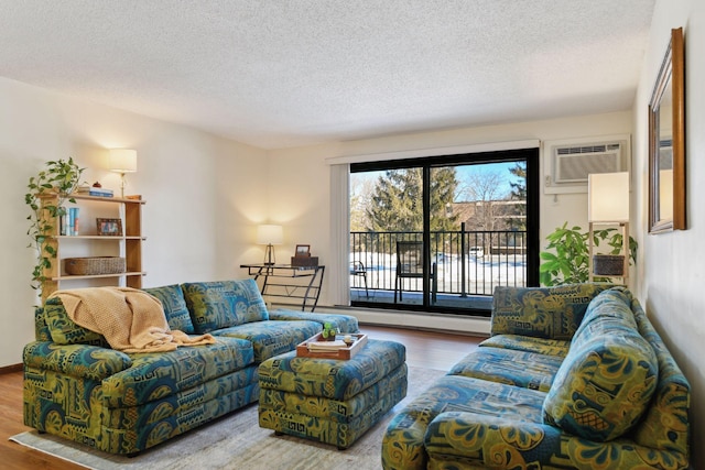 living area featuring a wall unit AC, a textured ceiling, and wood finished floors