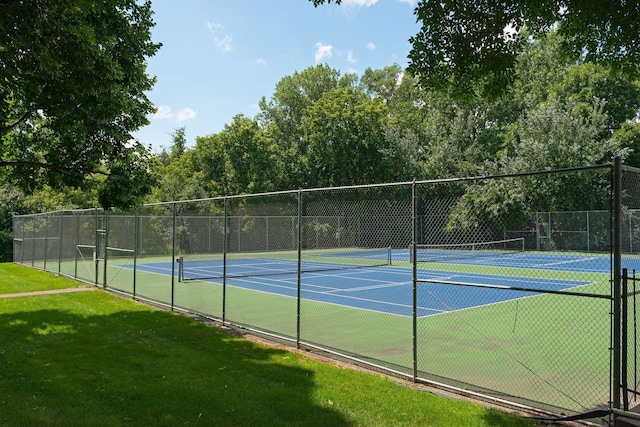 view of tennis court with fence and a yard