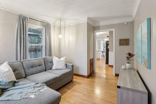 living room featuring light wood-style floors, ornamental molding, a textured ceiling, and baseboards