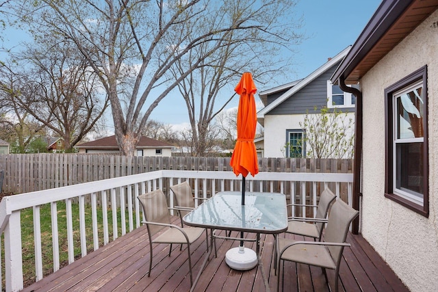 wooden terrace with a fenced backyard and outdoor dining area