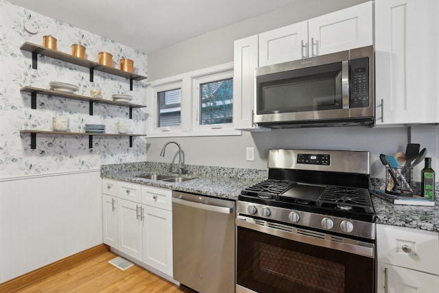 4244 Jefferson St NE, Columbia Heights, MN 55421 - kitchen featuring a sink, a wainscoted wall, stone countertops, light wood finished floors, and stainless steel appliances