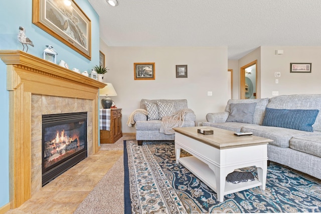 living room with a tile fireplace and a textured ceiling