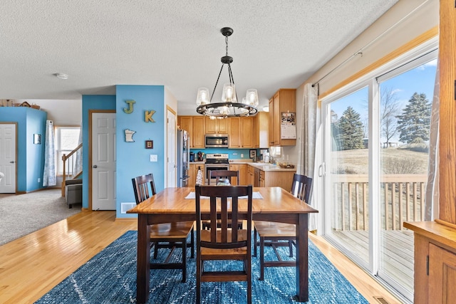 dining space featuring light wood-style floors, a notable chandelier, and a textured ceiling