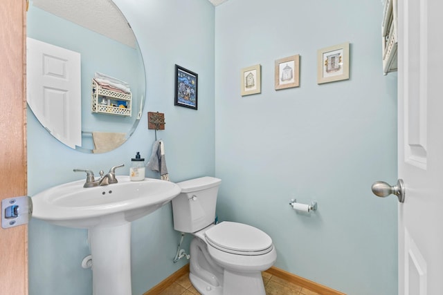 bathroom featuring a sink, tile patterned flooring, toilet, and baseboards