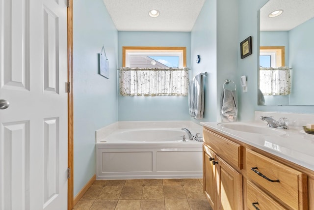 full bath featuring plenty of natural light, a textured ceiling, vanity, and a bath