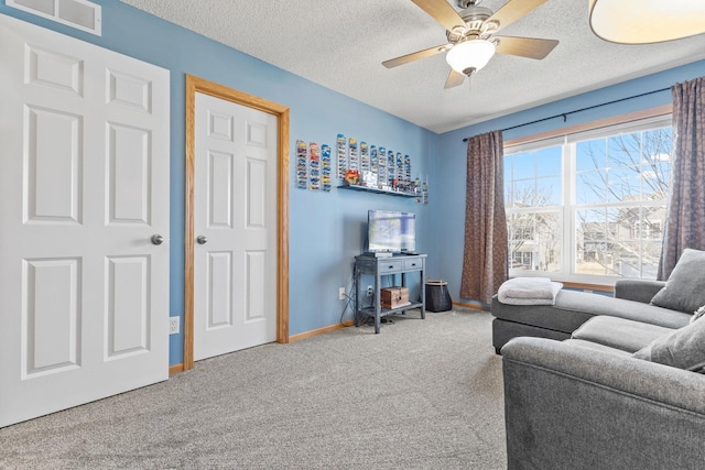 carpeted living area featuring a textured ceiling, baseboards, visible vents, and a ceiling fan