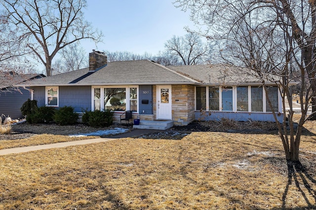 ranch-style home featuring a chimney and a shingled roof