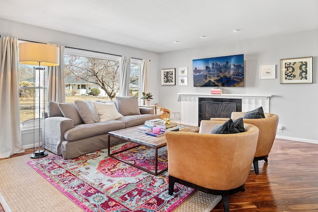 living area featuring a tiled fireplace, wood finished floors, and baseboards
