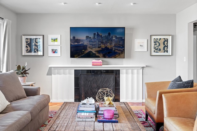 living room with wood finished floors, baseboards, and a brick fireplace