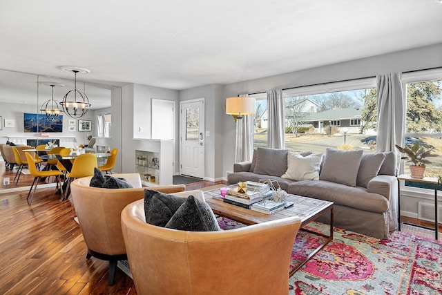 living area with visible vents, a notable chandelier, hardwood / wood-style floors, and baseboards
