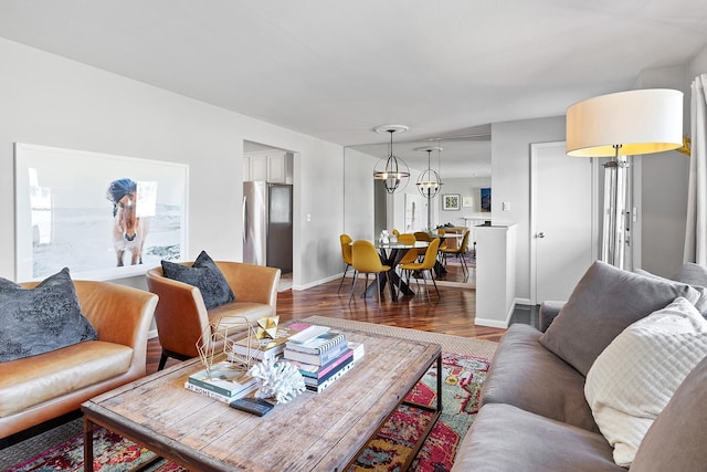living room featuring baseboards, a notable chandelier, and wood finished floors