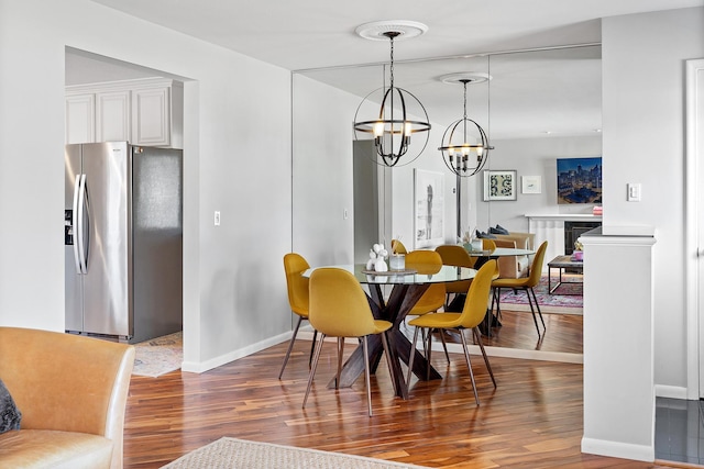 dining space featuring a chandelier, wood finished floors, and baseboards