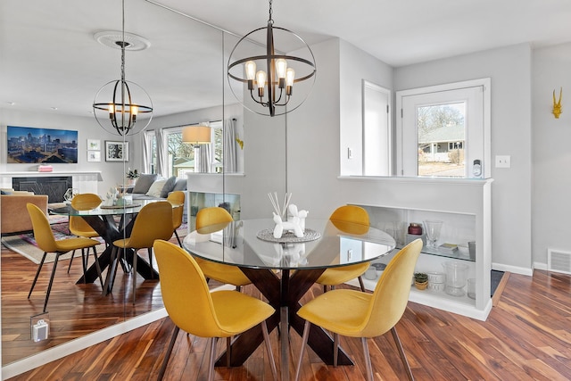 dining area featuring wood finished floors, visible vents, a notable chandelier, and baseboards