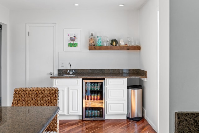 bar with dark wood finished floors, indoor wet bar, recessed lighting, a sink, and beverage cooler