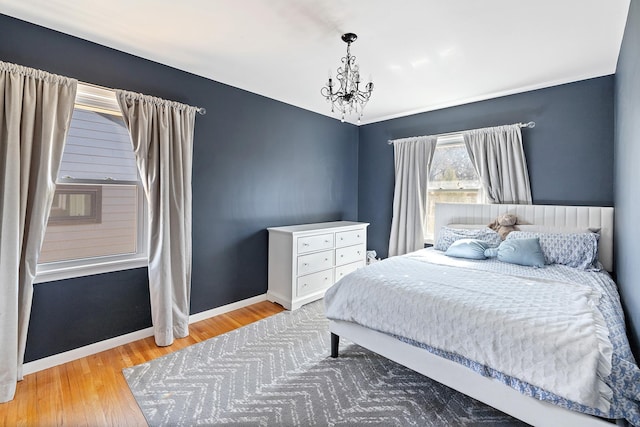 bedroom featuring a chandelier, wood finished floors, and baseboards