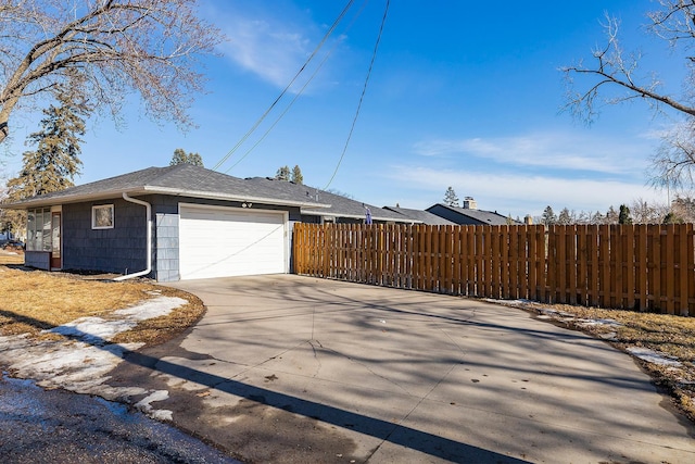 view of side of home featuring concrete driveway, a garage, and fence