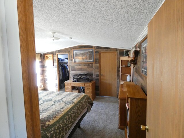 bedroom featuring wooden walls, lofted ceiling, carpet flooring, and a textured ceiling