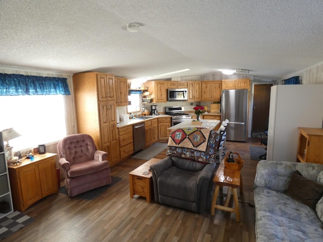 living room featuring vaulted ceiling, sink, hardwood / wood-style floors, and a textured ceiling