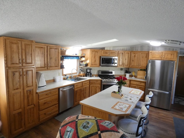 kitchen with sink, a center island, vaulted ceiling, appliances with stainless steel finishes, and dark hardwood / wood-style flooring