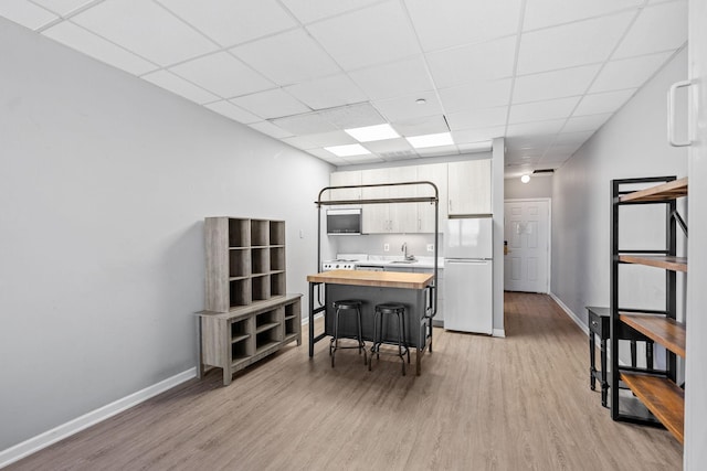 interior space featuring sink, a breakfast bar, wooden counters, white refrigerator, and light wood-type flooring