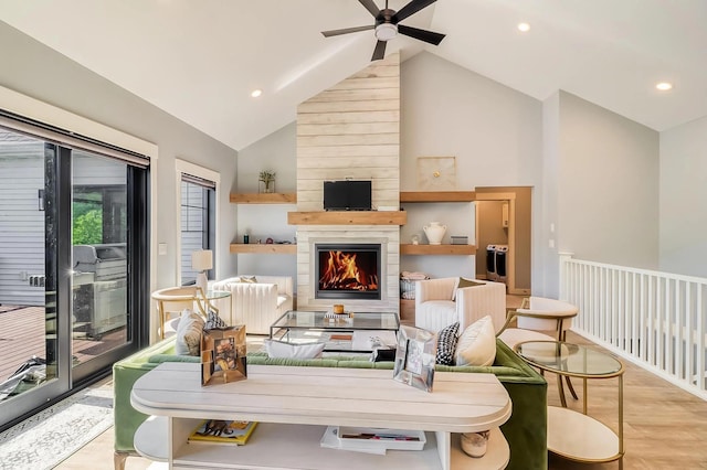 living room with ceiling fan, high vaulted ceiling, a large fireplace, and light hardwood / wood-style floors