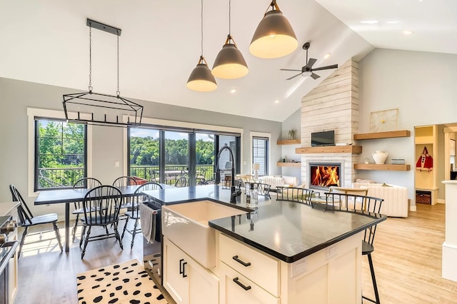 kitchen with a kitchen island with sink, decorative light fixtures, a fireplace, and a breakfast bar area