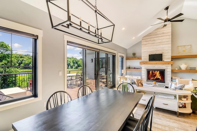 dining room with ceiling fan, high vaulted ceiling, a fireplace, and light hardwood / wood-style floors