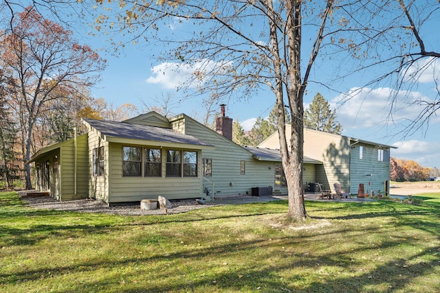 rear view of house featuring a patio, central AC unit, a chimney, and a lawn