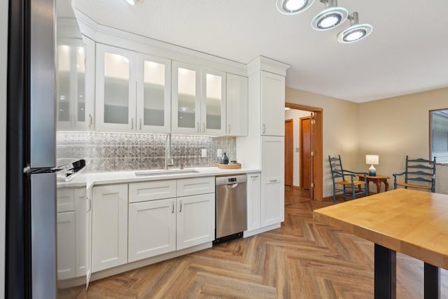 kitchen with stainless steel appliances, a sink, white cabinets, light countertops, and backsplash