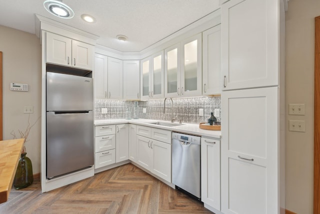 kitchen featuring stainless steel appliances, light countertops, a sink, and white cabinetry