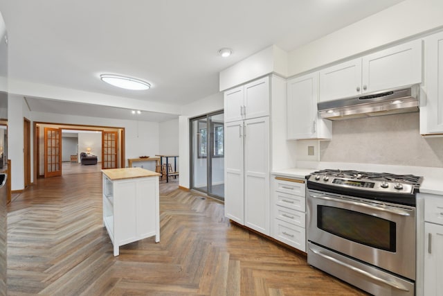 kitchen with stainless steel gas range, light countertops, under cabinet range hood, and white cabinetry