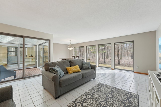 living room featuring light tile patterned flooring, a textured ceiling, and baseboards