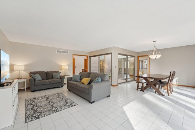 living area featuring light tile patterned floors, baseboards, and visible vents