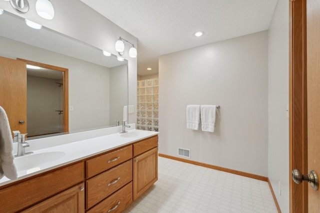 bathroom featuring visible vents, a sink, baseboards, and double vanity