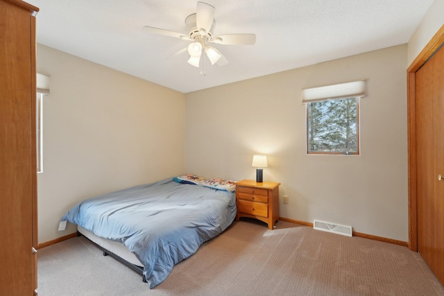 bedroom featuring baseboards, visible vents, a ceiling fan, and light colored carpet