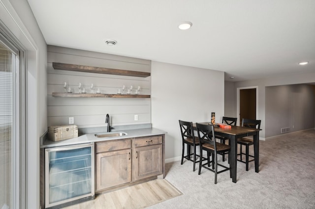 bar featuring sink, light carpet, and wine cooler